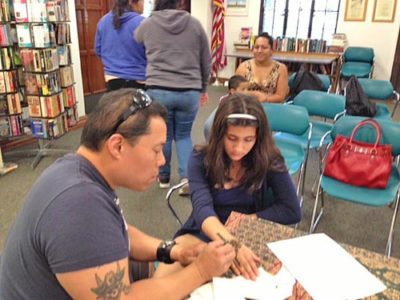 HENNA TATTOOS are one of the activities at Memorial Library in March. Here Russell Chan shows a teen how its done. 